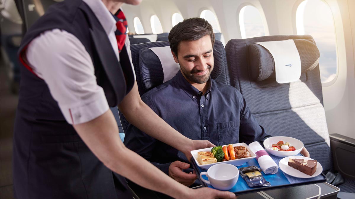 Man being served a meal in World Traveller Plus.