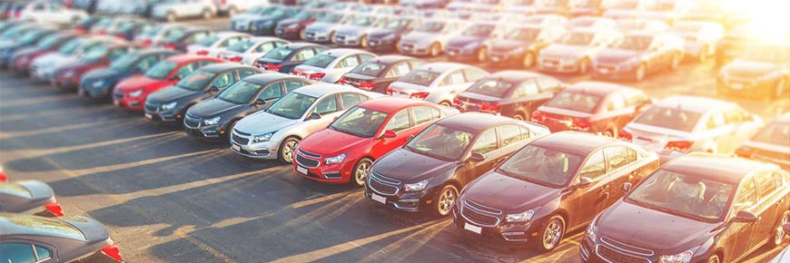 An image of a bright sunny car park full of parked cars.
