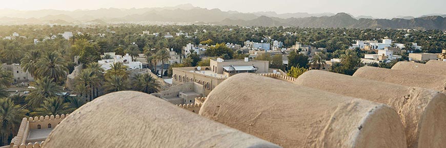 City against mountain range at idyllic sunset. Nizwa in Sultanate of Oman.