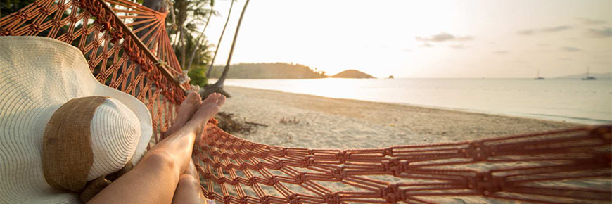Young woman on a tropical beach in Thailand relaxing on a hammock.