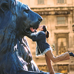 A woman kissing lion statue at Trafalgar Square in London.