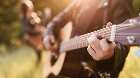 Persone che suonano la chitarra illuminati dalla luce del sole.