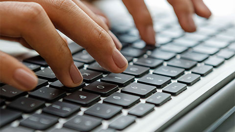 Close up of hands typing on a keyboard.