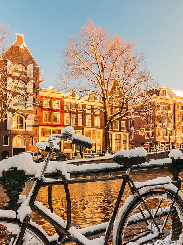 Snowy bicycles alongside a canal during winter in Amsterdam. © DutchScenery