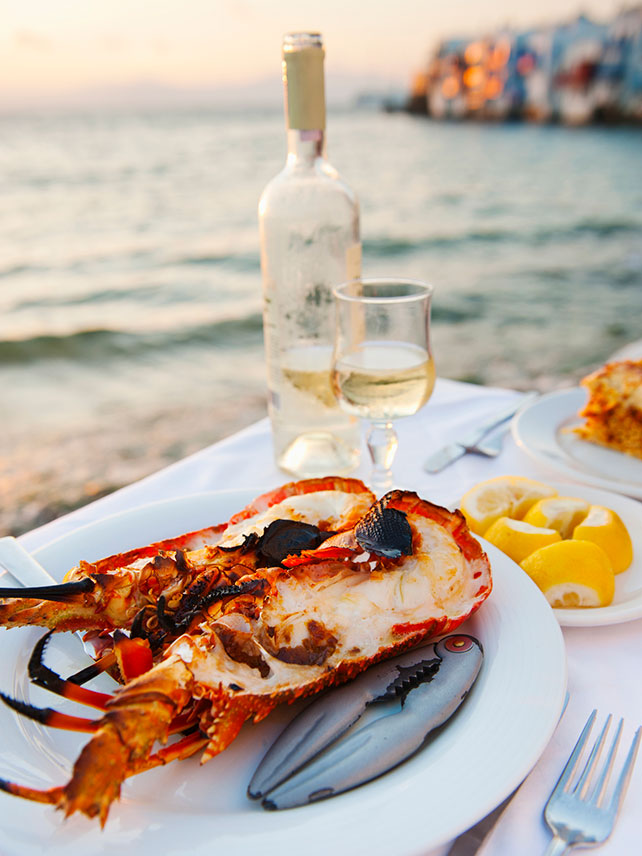 Enjoy a lobster dinner by the coast in Mykonos. ©Tetra Images.