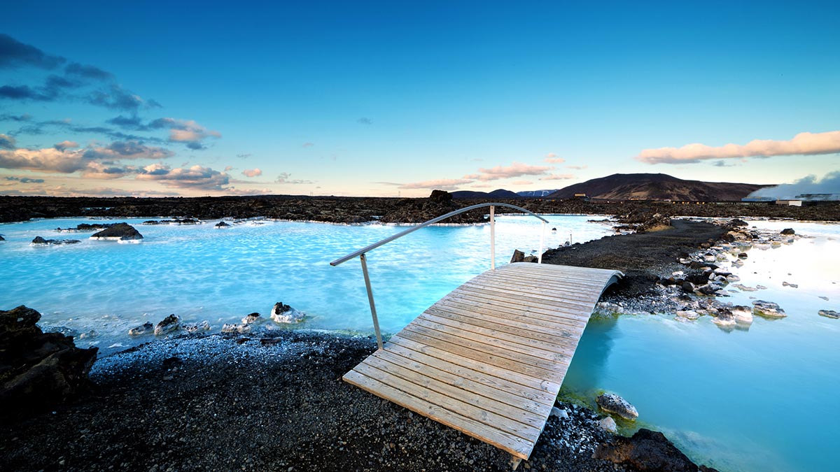 Small footbridge over vivid aquamarine waters of Blue Lagoon hot springs on Reykjanes Peninsula, Iceland.